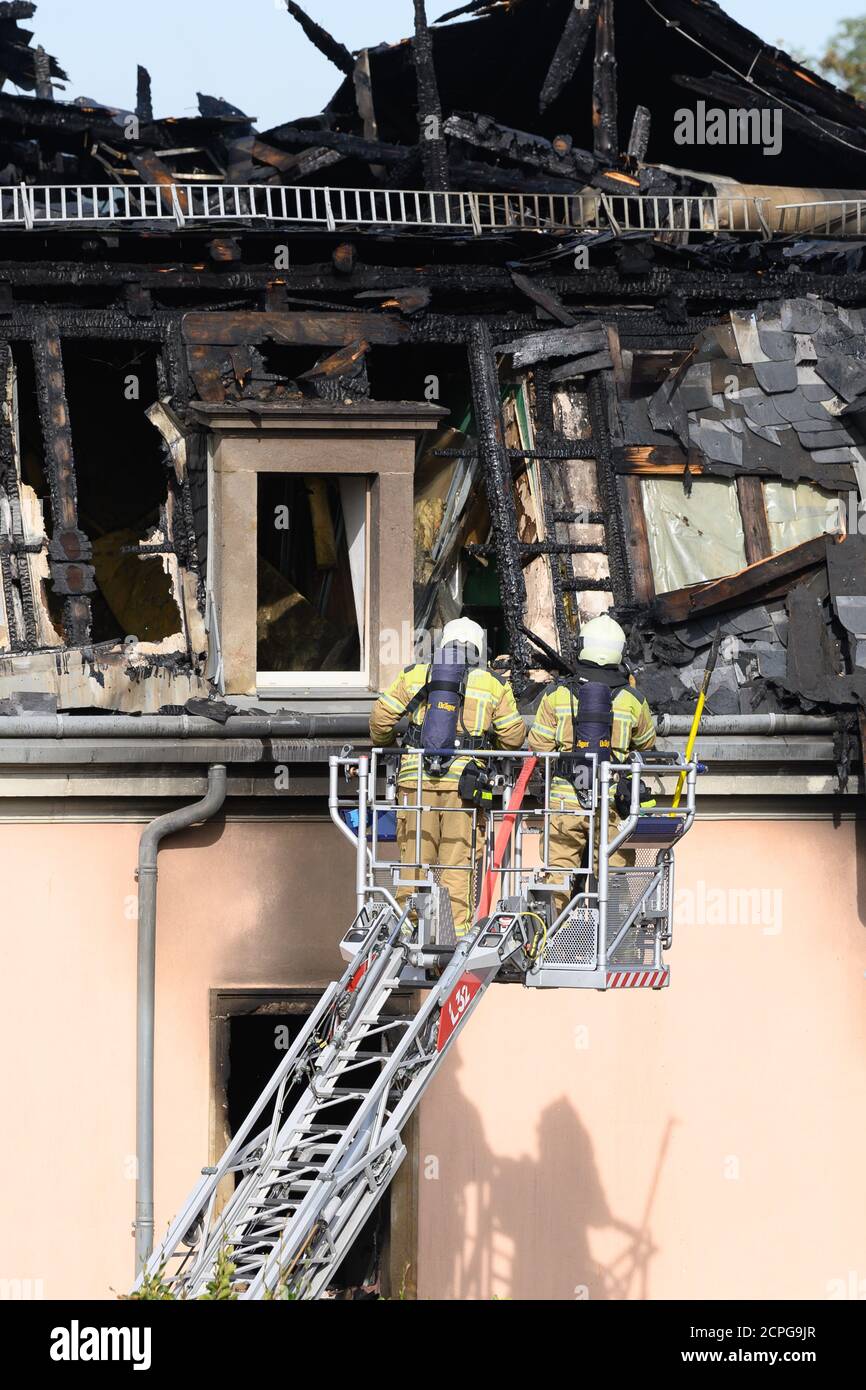 Dresda, Germania. 19 Settembre 2020. I vigili del fuoco ispezionano il traliccio del tetto da una scala giradischi dopo un incendio in un edificio di appartamenti. Si dice che il fuoco sia iniziato in un appartamento al secondo piano e poi si è allargato alla capriata del tetto attraverso il controsoffitto. Un uomo ha cercato di salvarsi dal fuoco saltando fuori dalla finestra della casa il sabato mattina. Gli è stato immediatamente dato cure mediche di emergenza e portato in un ospedale. Non ci sono state altre lesioni. Credit: Sebastian Kahnert/dpa-Zentralbild/dpa/Alamy Live News Foto Stock