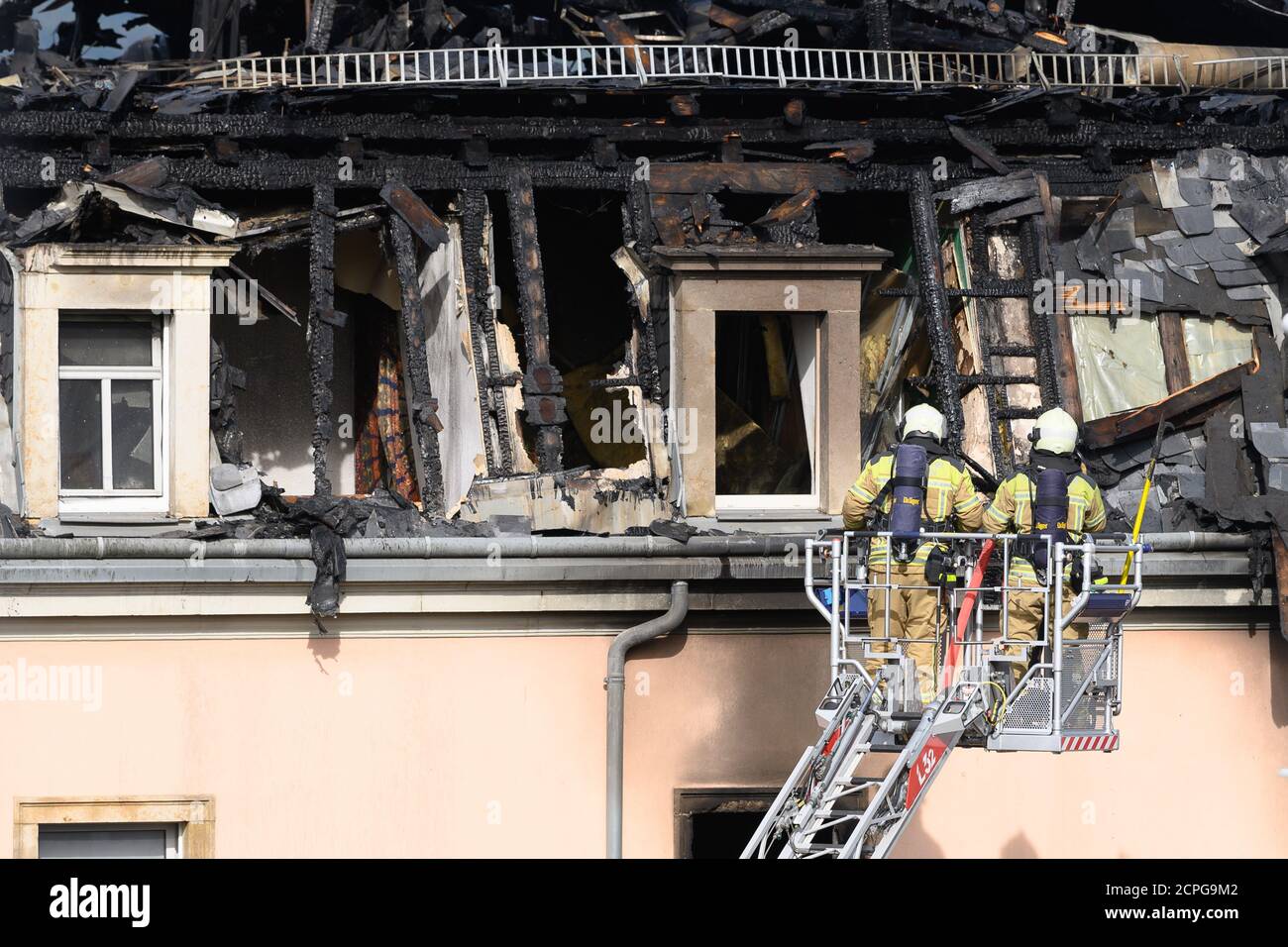 Dresda, Germania. 19 Settembre 2020. I vigili del fuoco ispezionano il traliccio del tetto da una scala giradischi dopo un incendio in un edificio di appartamenti. Si dice che il fuoco sia iniziato in un appartamento al secondo piano e poi si è allargato alla capriata del tetto attraverso il controsoffitto. Un uomo ha cercato di salvarsi dal fuoco saltando fuori dalla finestra della casa il sabato mattina. Gli è stato immediatamente dato cure mediche di emergenza e portato in un ospedale. Non ci sono state altre lesioni. Credit: Sebastian Kahnert/dpa-Zentralbild/dpa/Alamy Live News Foto Stock