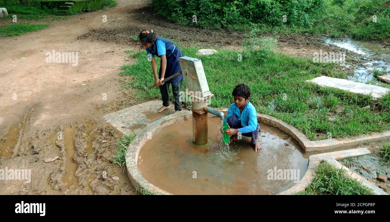 DISTRETTO KATNI, INDIA - 04 AGOSTO 2019: i bambini della scuola di governo indiano che bevono l'acqua dalla pompa a mano all'area del villaggio. Foto Stock