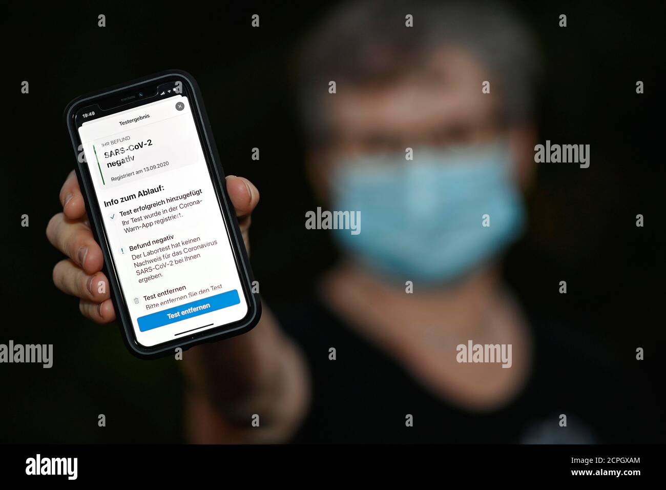 Risultato negativo del test, persona con guardia bocca mostra smartphone con Corona WARN-APP, crisi Corona, Baden-Württemberg, Germania, Europa Foto Stock