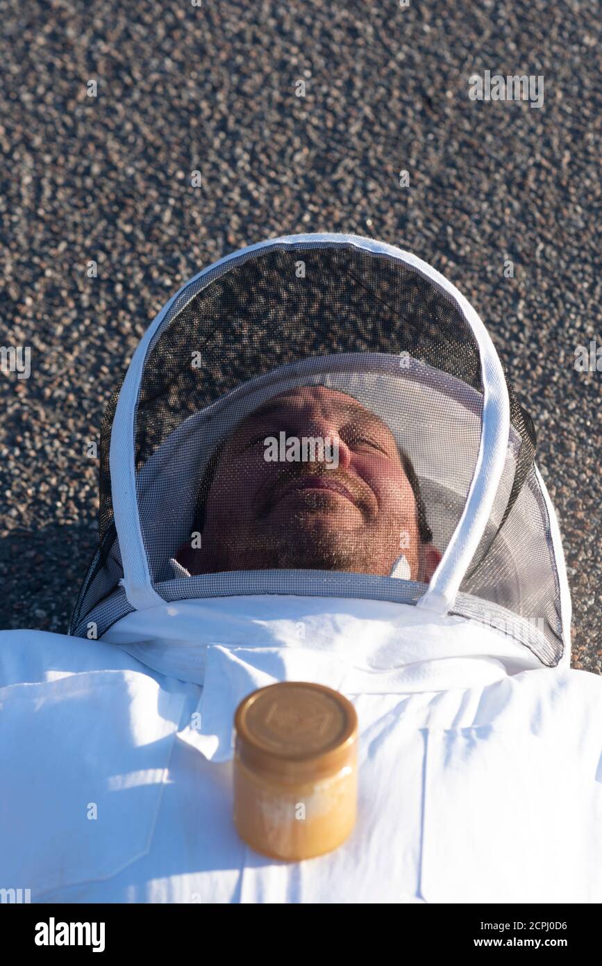 L'apicoltore si trova su una strada asfaltata Foto Stock