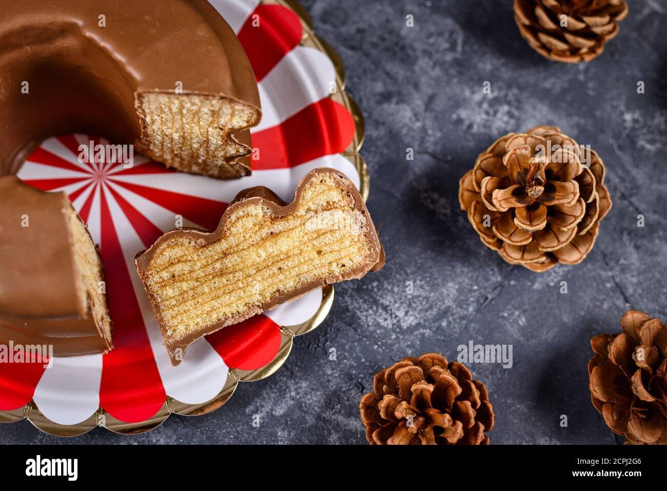 Fetta di torta invernale a strati tedesca tradizionale chiamata 'Baumkuchen' smaltata con cioccolato che mostra strati sottili all'interno della torta Foto Stock