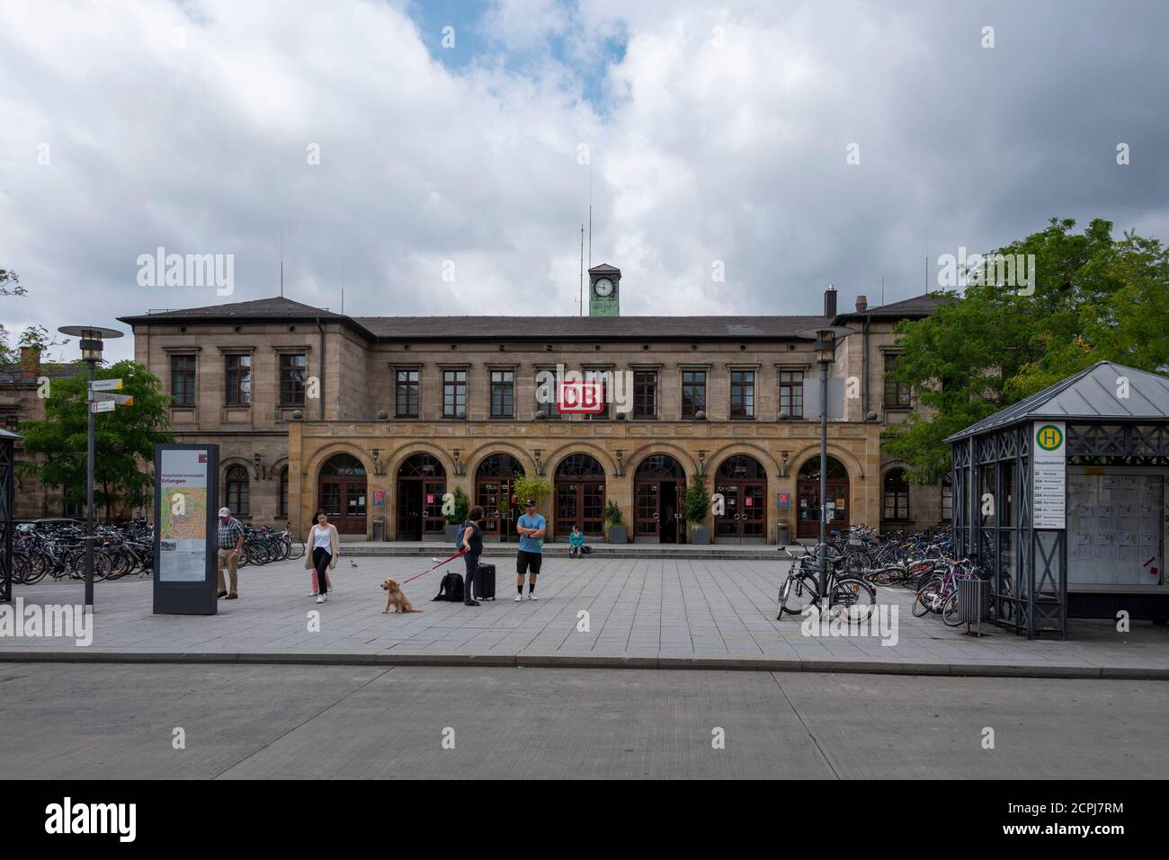 Germania, Baviera, Erlangen, stazione centrale, piazzale, logo DB, facciata casa, passers-by con cane. Foto Stock