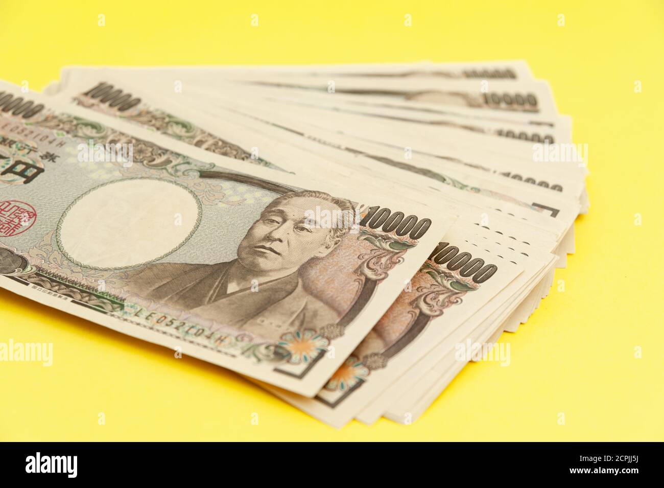 Diecimila yen (10,000 yen) banconote accatastate. Denaro giapponese. Carta denaro. Isolato su sfondo giallo. Vista dall'alto. Foto Stock
