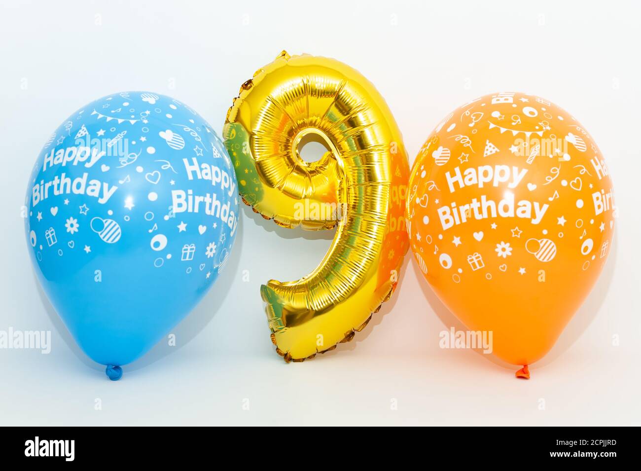 Numero gonfiabile 9 colore dorato metallizzato brillante con palloncini blu e giallo isolati su sfondo bianco. Primo piano. Shot orizzontale. Foto Stock