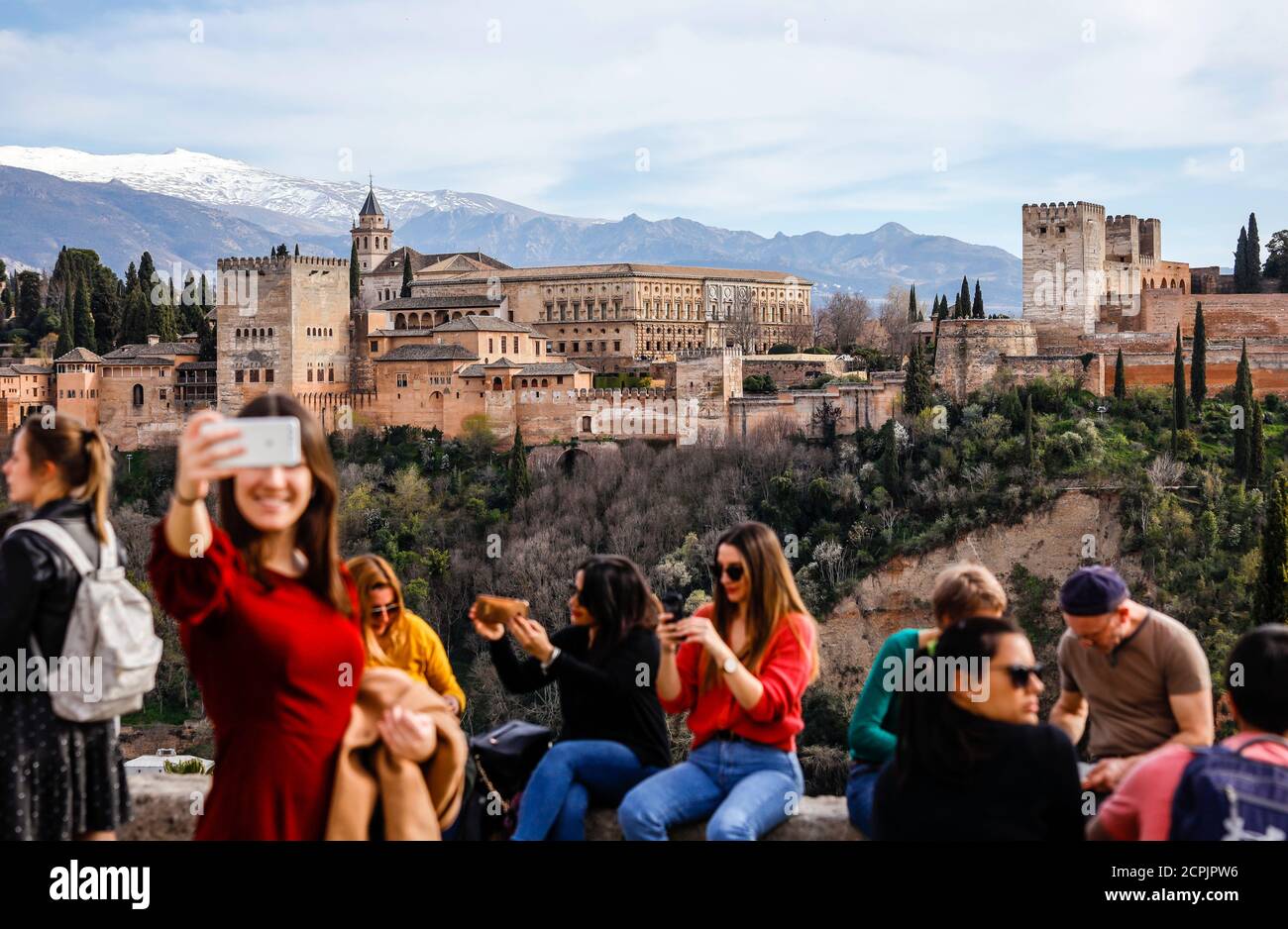 I turisti scattano foto con il castello moresco Alhambra, i palazzi Nasrid, il Palazzo Karl V., la Sierra Nevada coperta di neve sul retro, Granada, Foto Stock