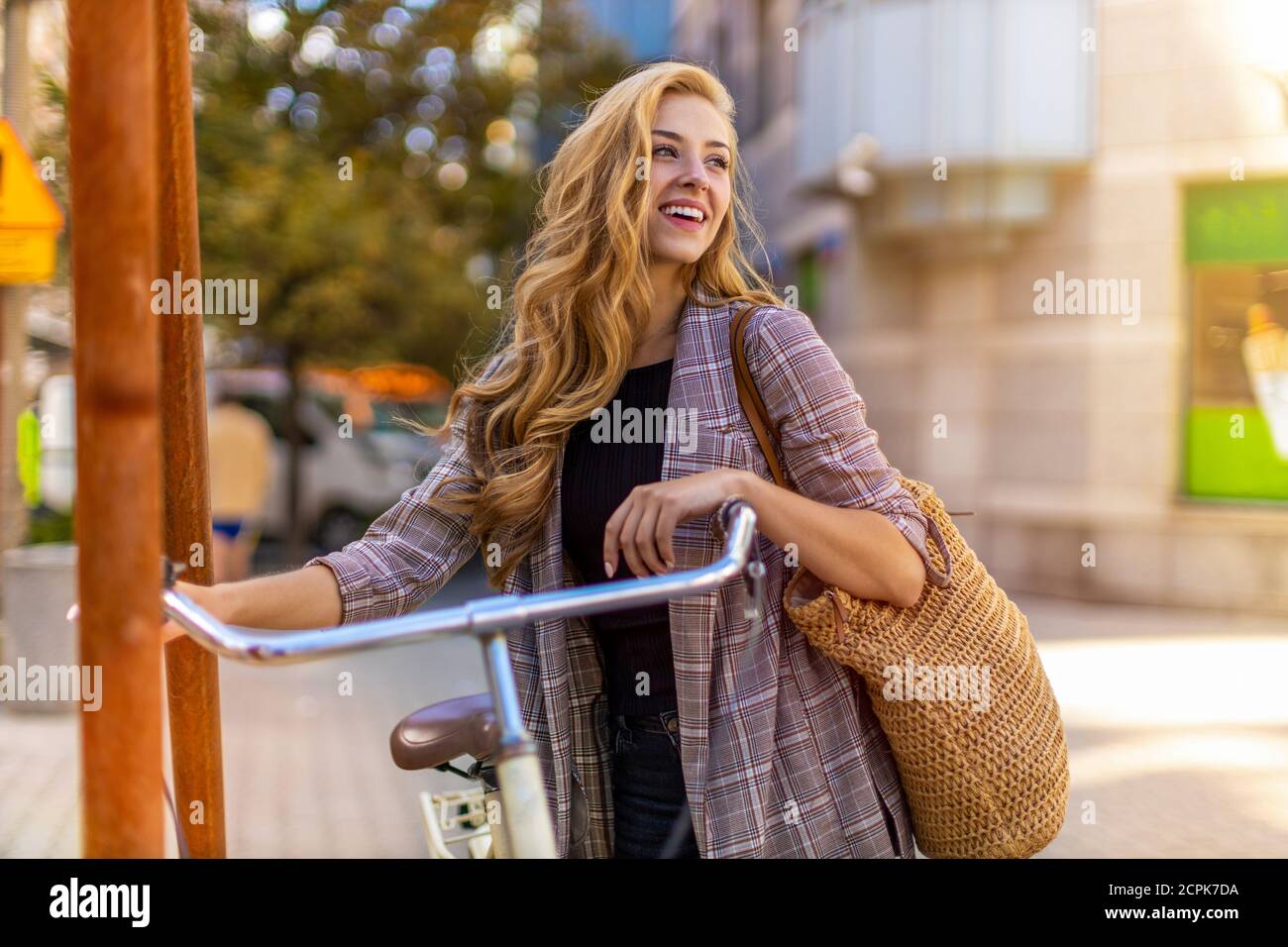 Giovane donna con la bicicletta in città Foto Stock