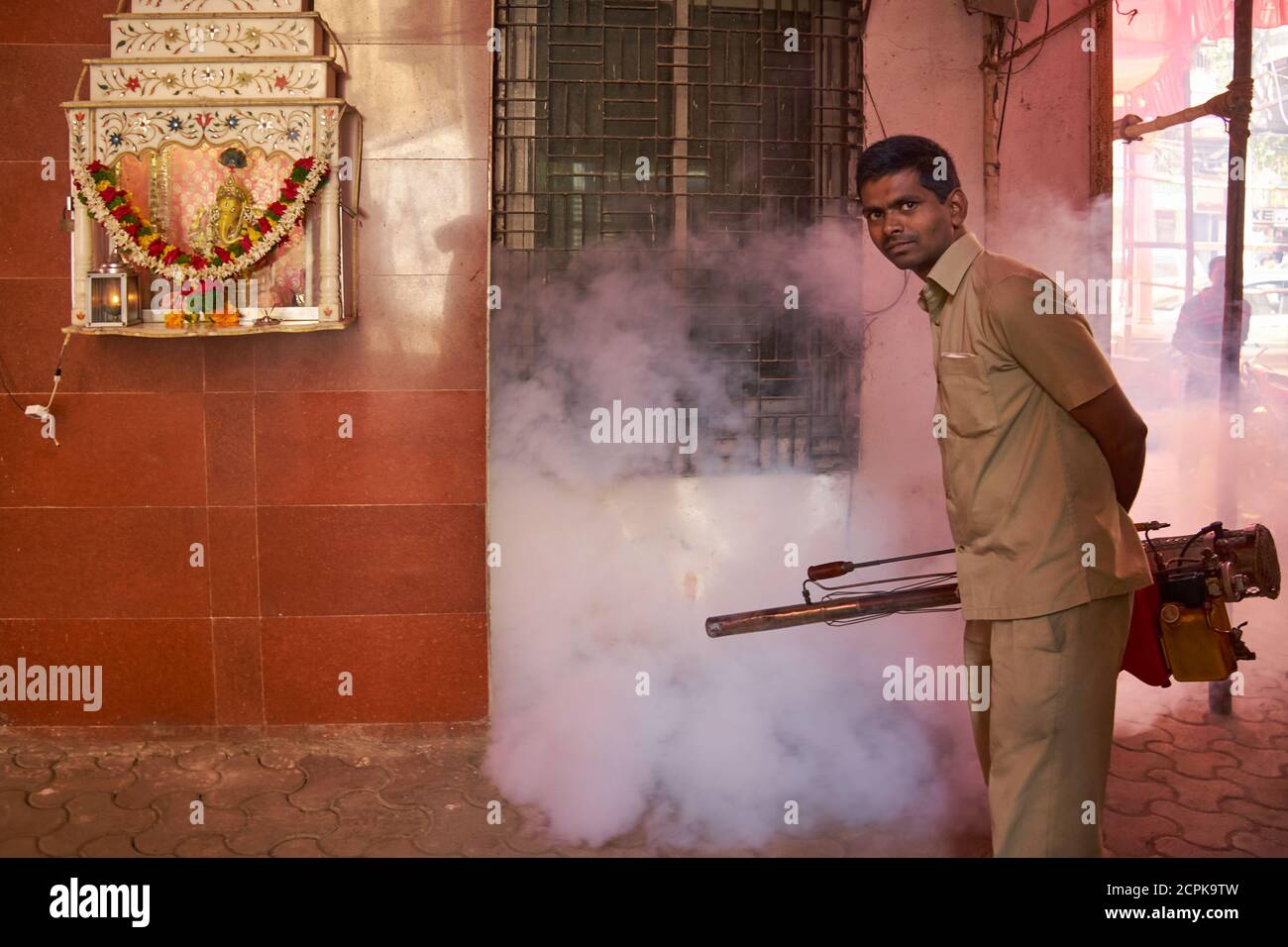 Prima dell'inizio della stagione delle piogge, un operaio municipale di Mumbai, in India, spruzzi la zona intorno ad un santuario indù con pesticidi per il controllo delle zanzare Foto Stock