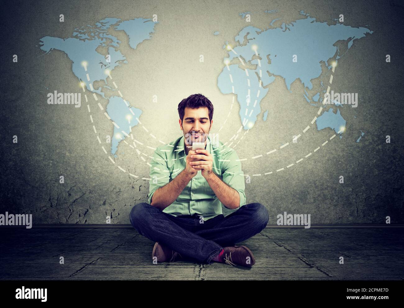 Moderna tecnologia di comunicazione telefono cellulare high tech, concetto di connessione web. Uomo felice seduto su un pavimento utilizzando smartphone connesso navigazione inter Foto Stock