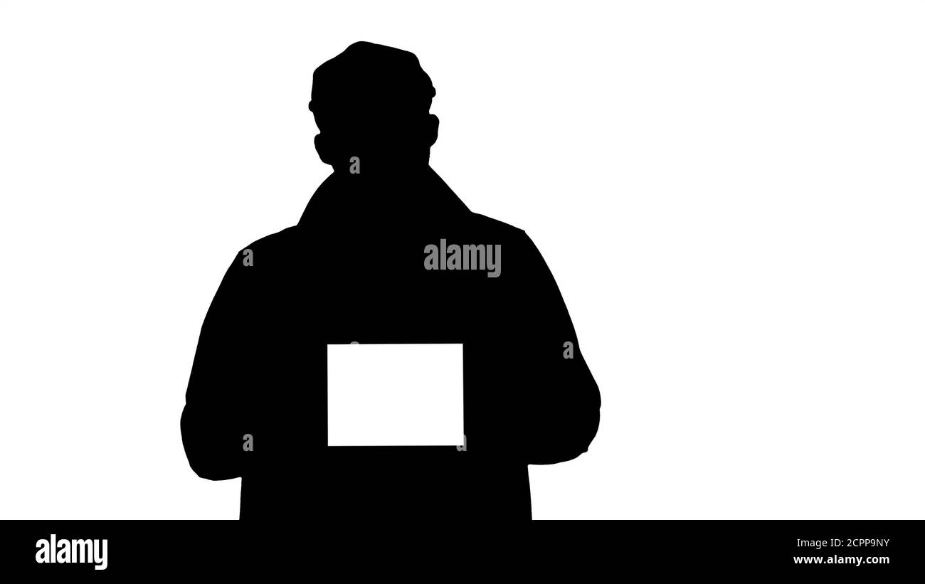 Silhouette uomo in trench walking e reggendo tablet con bianco s Foto Stock