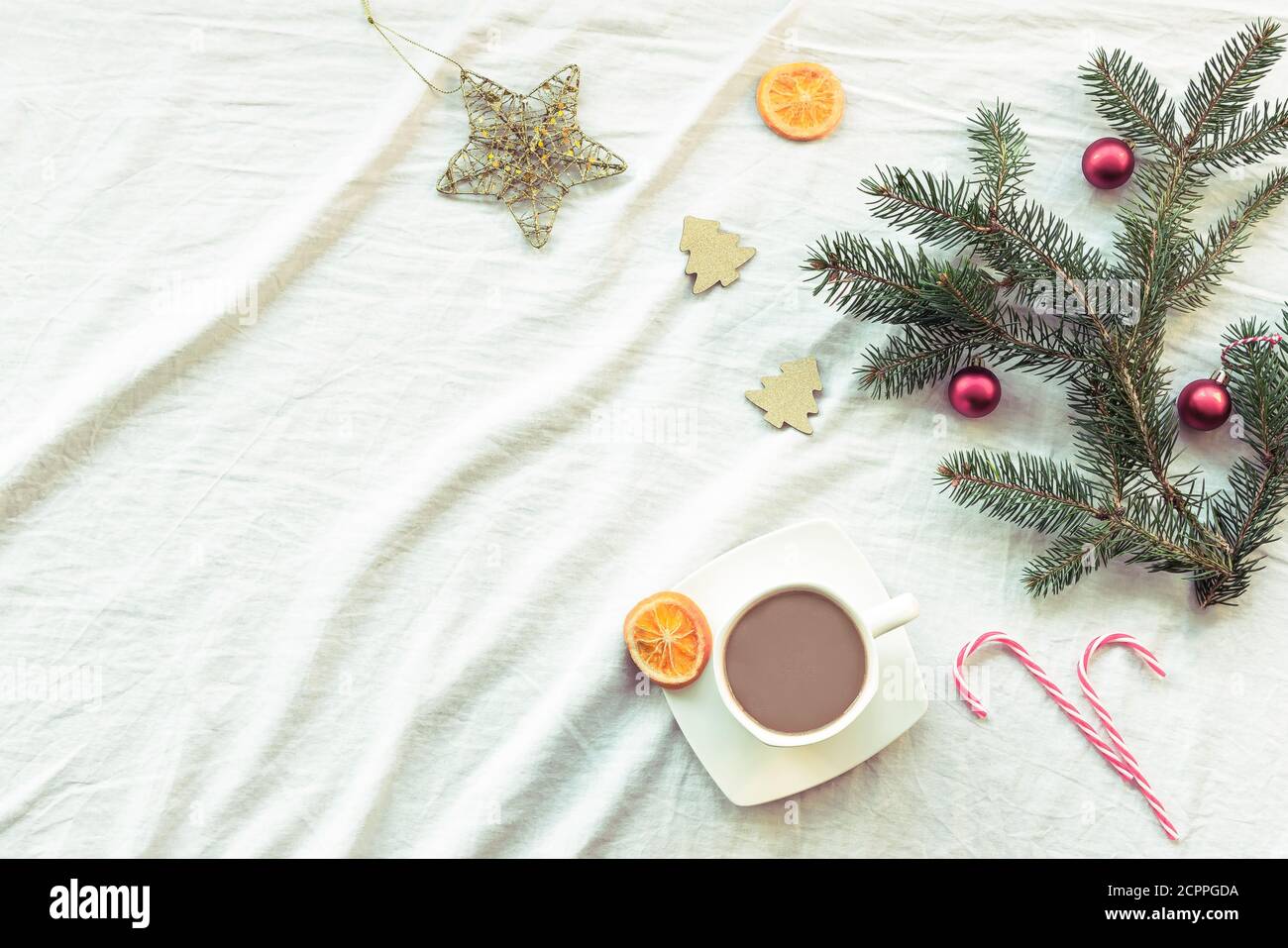 Layout di Capodanno con tazza di caffè o cacao, rami di abete, decorazioni natalizie, caramelle a bastone, arance secche. Vista dall'alto, disposizione piatta, spazio per la copia. Foto Stock