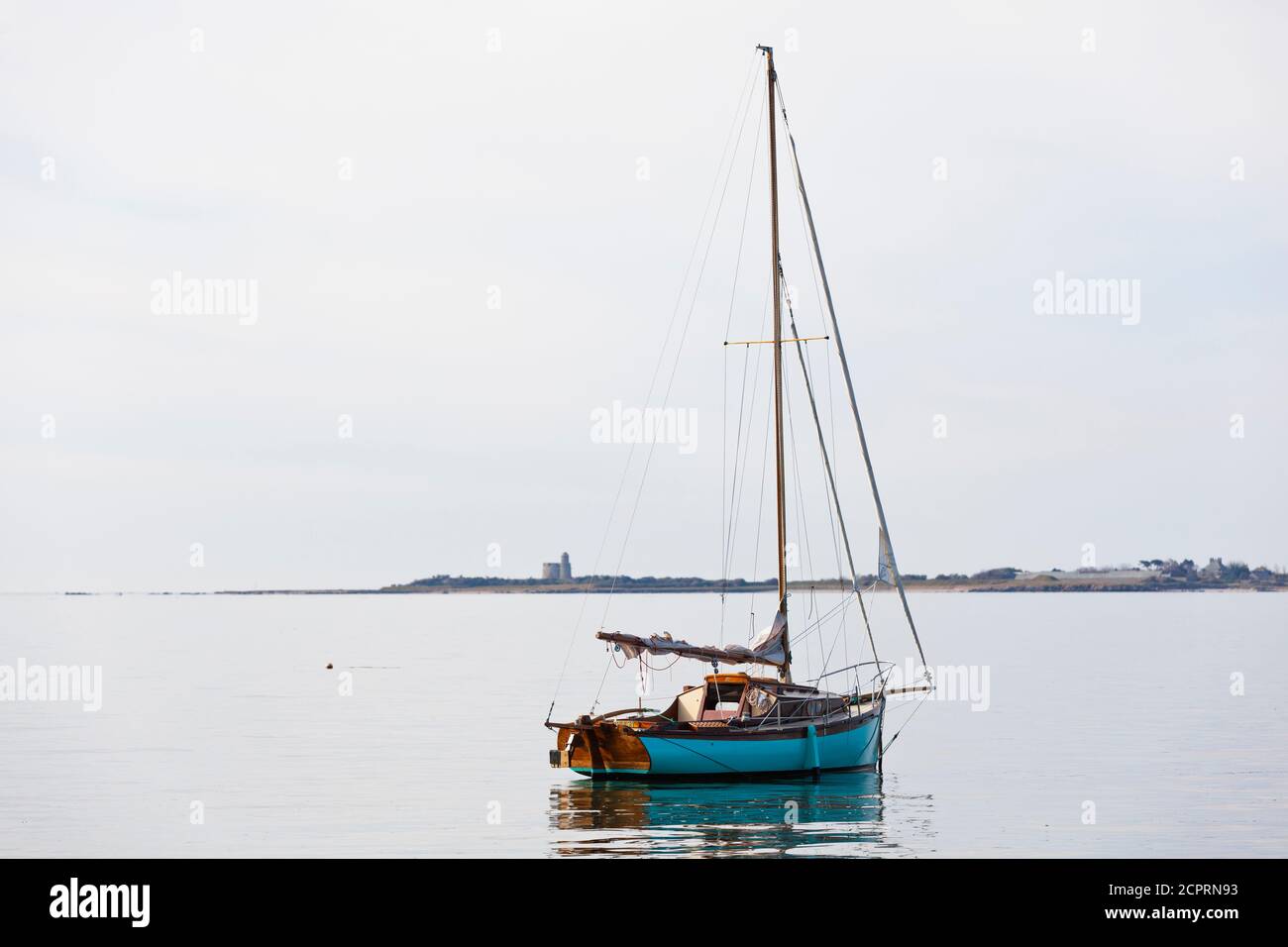 Barca a vela all'ancora a Saint Vaast la Hougue, sullo sfondo l'isola di Ile Tatihou. Penisola del Cotentin, Normandia, Francia Foto Stock