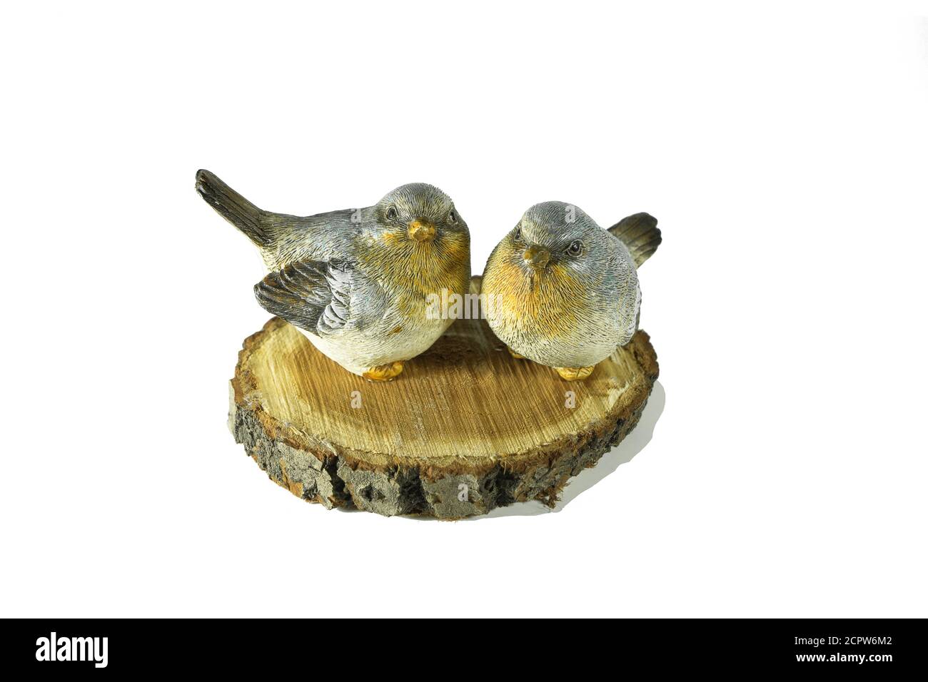 Due piccoli uccelli in ceramica grigio e giallo siedono su una sega di betulla naturale tagliata isolata su sfondo bianco. Decorazioni interne. Foto Stock