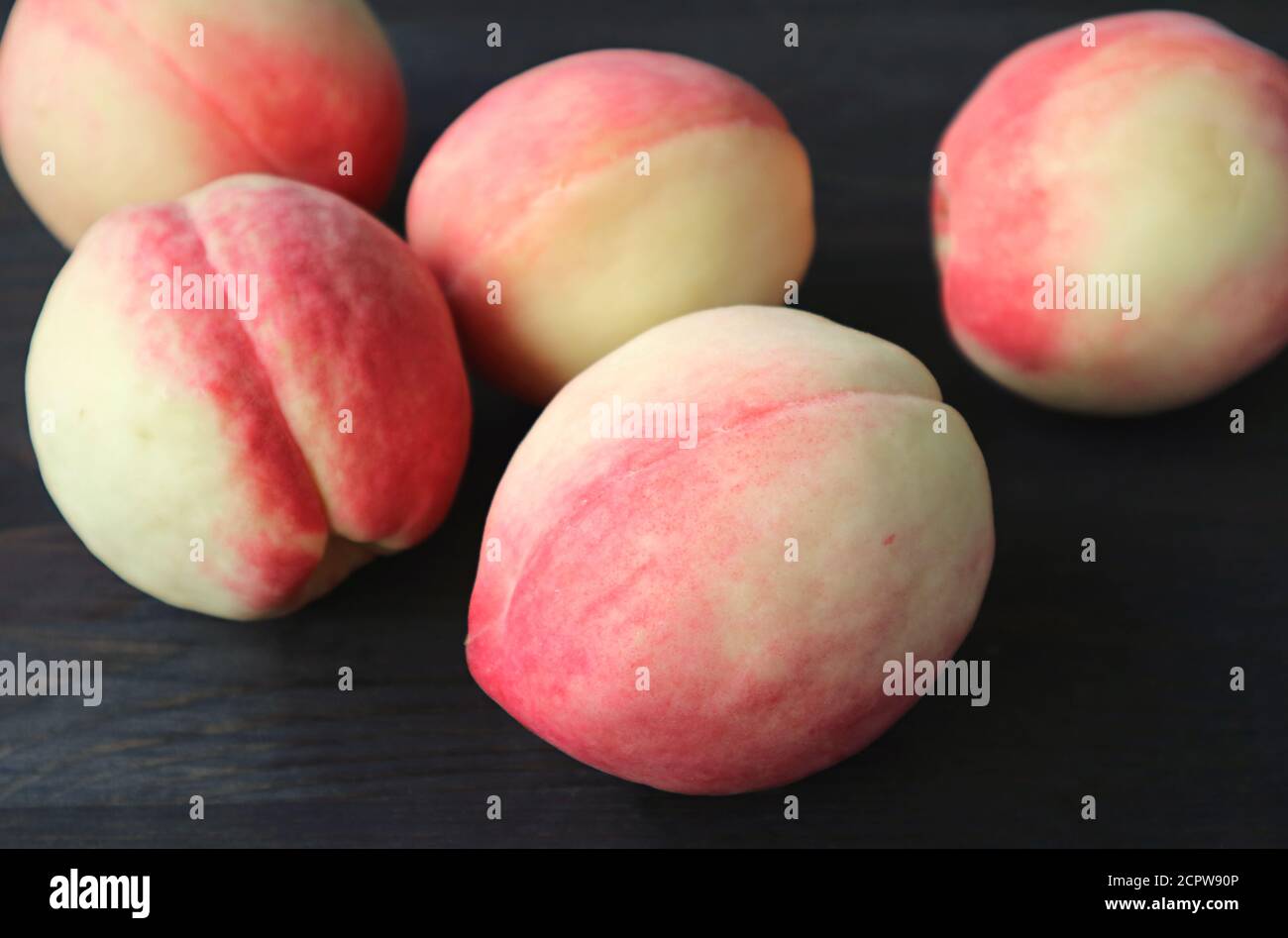 Closeup fresche pesche mature Scattered su tavola di legno nero Foto Stock