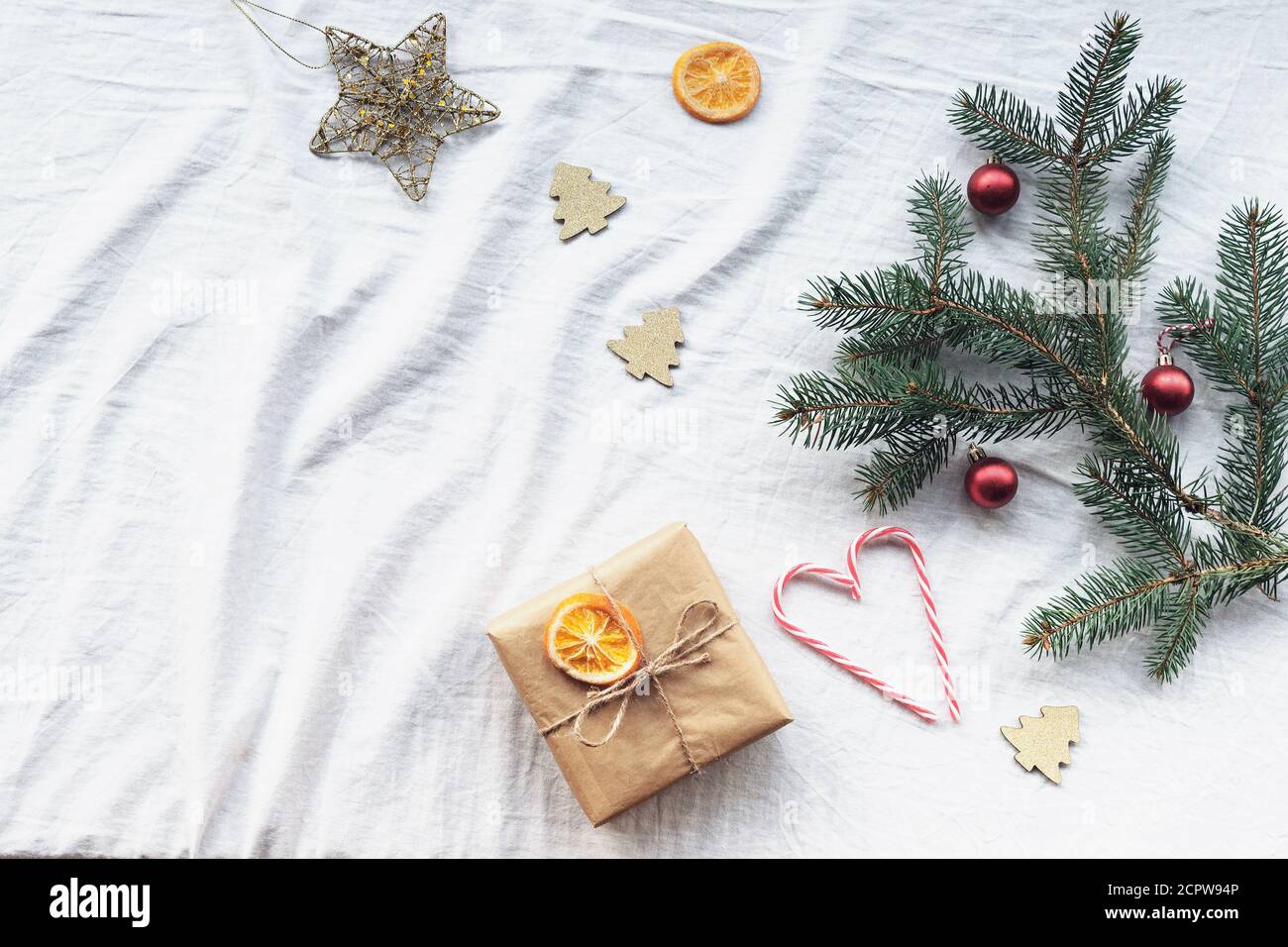 Layout di Capodanno con confezione regalo, rami di abete, decorazioni natalizie, caramelle bastone, arance secche. Vista dall'alto, disposizione piatta, spazio per la copia. Foto Stock