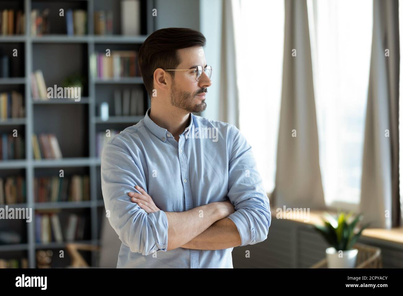 Il giovane uomo caucasico pensivo guarda a distanza pensando Foto Stock