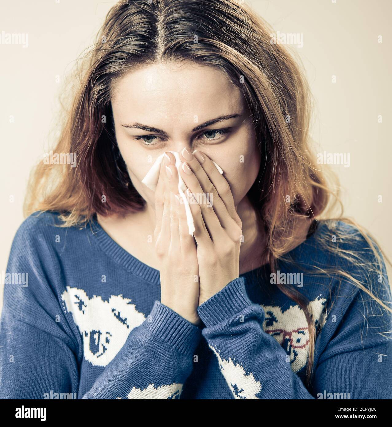 giovane donna prendere freddo e naso stripante con tovagliolo Foto Stock