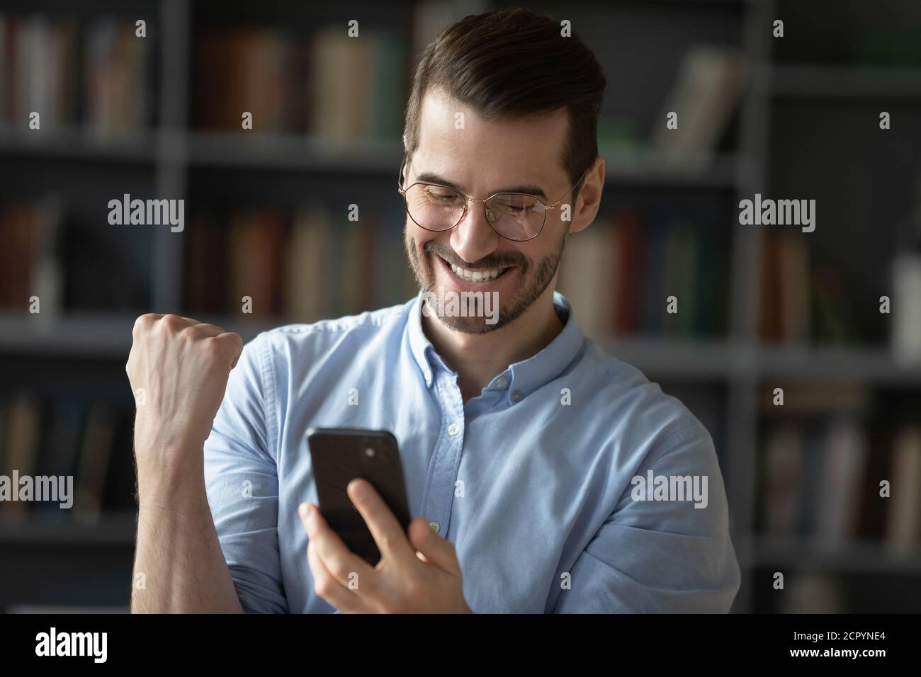 L'uomo eccitato sente euforico leggere il messaggio sul cellulare Foto Stock