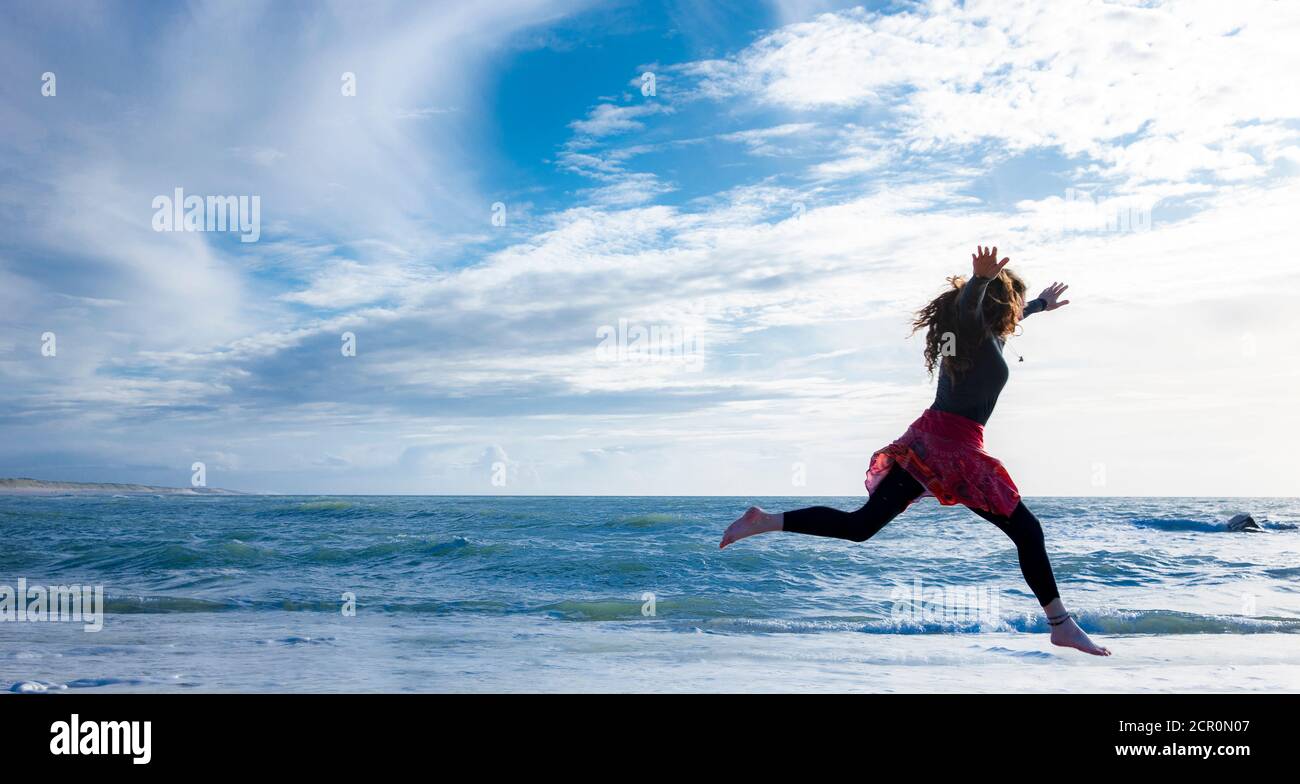 Donna con capelli lunghi che corrono sulla spiaggia Foto Stock