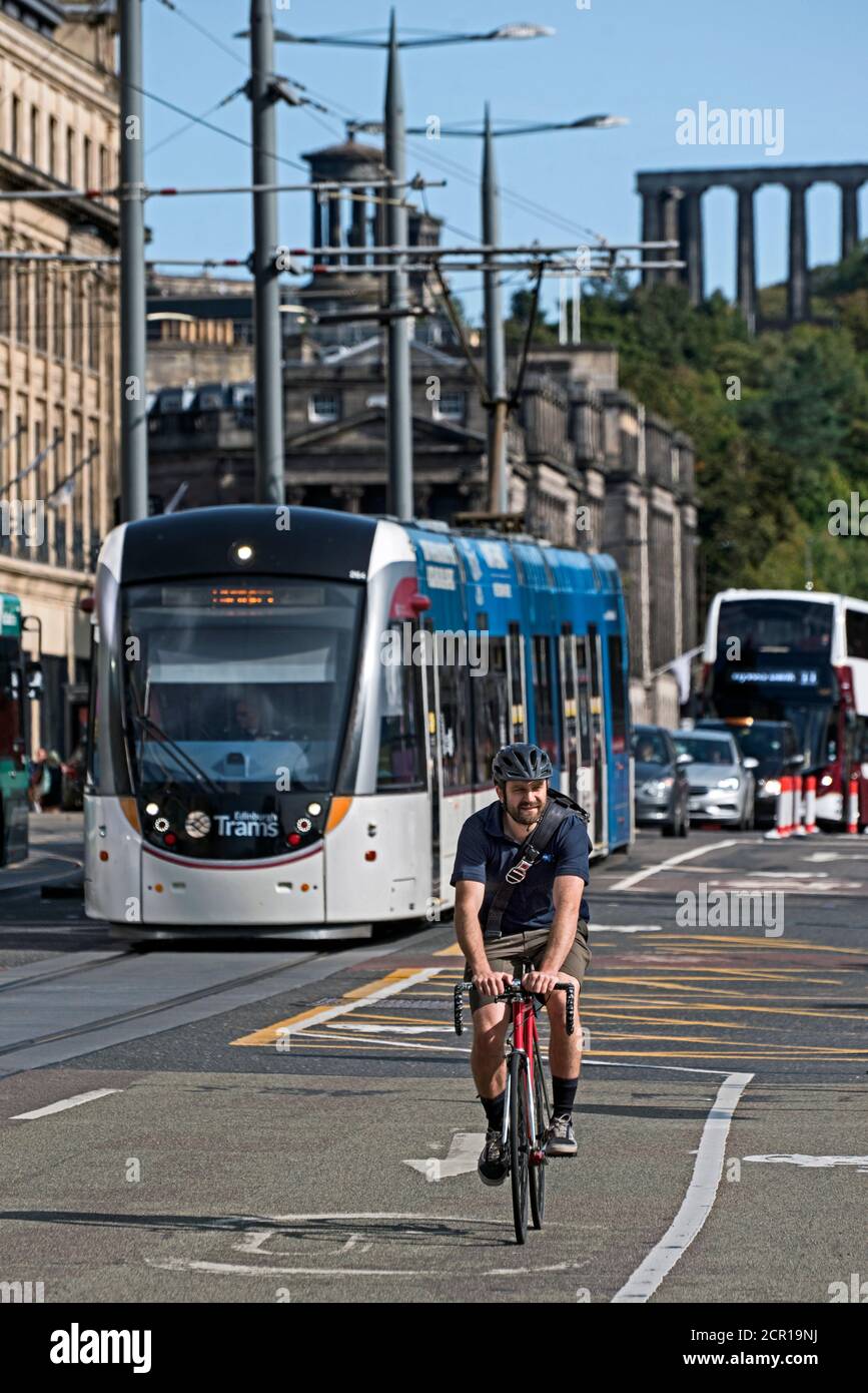Ciclista maschile su Princes Street con un tram sullo sfondo. Foto Stock