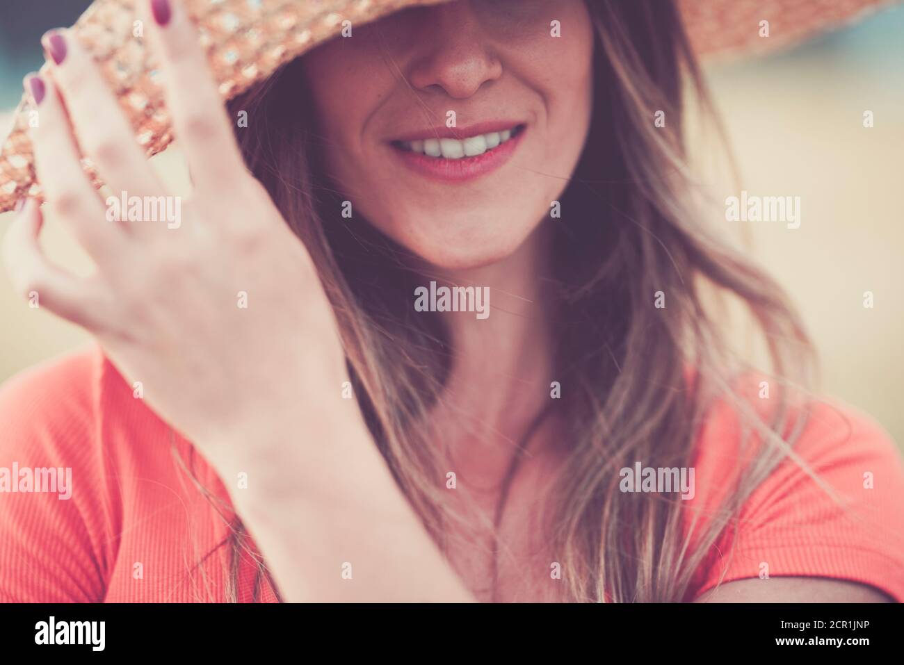 Primo piano ritratto donna in tonalità rosa vintage con allegro e felici occhi nascosti giovane donna caucasica con lungo bella capelli e cappello - concetto di Foto Stock