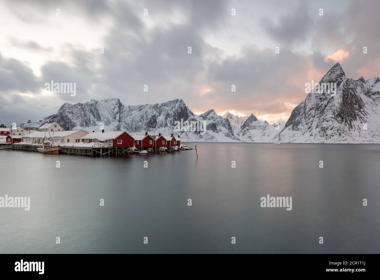 Paesaggio delle Isole Lofoten in Norvegia con legno tradizionale capanne di pescatori rossi di fronte al mare e questo bella moutain sullo sfondo Foto Stock