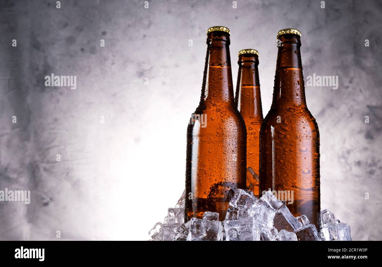 Birra leggera fredda con gocce d'acqua, bottiglie di birra con cubetti di ghiaccio Foto Stock