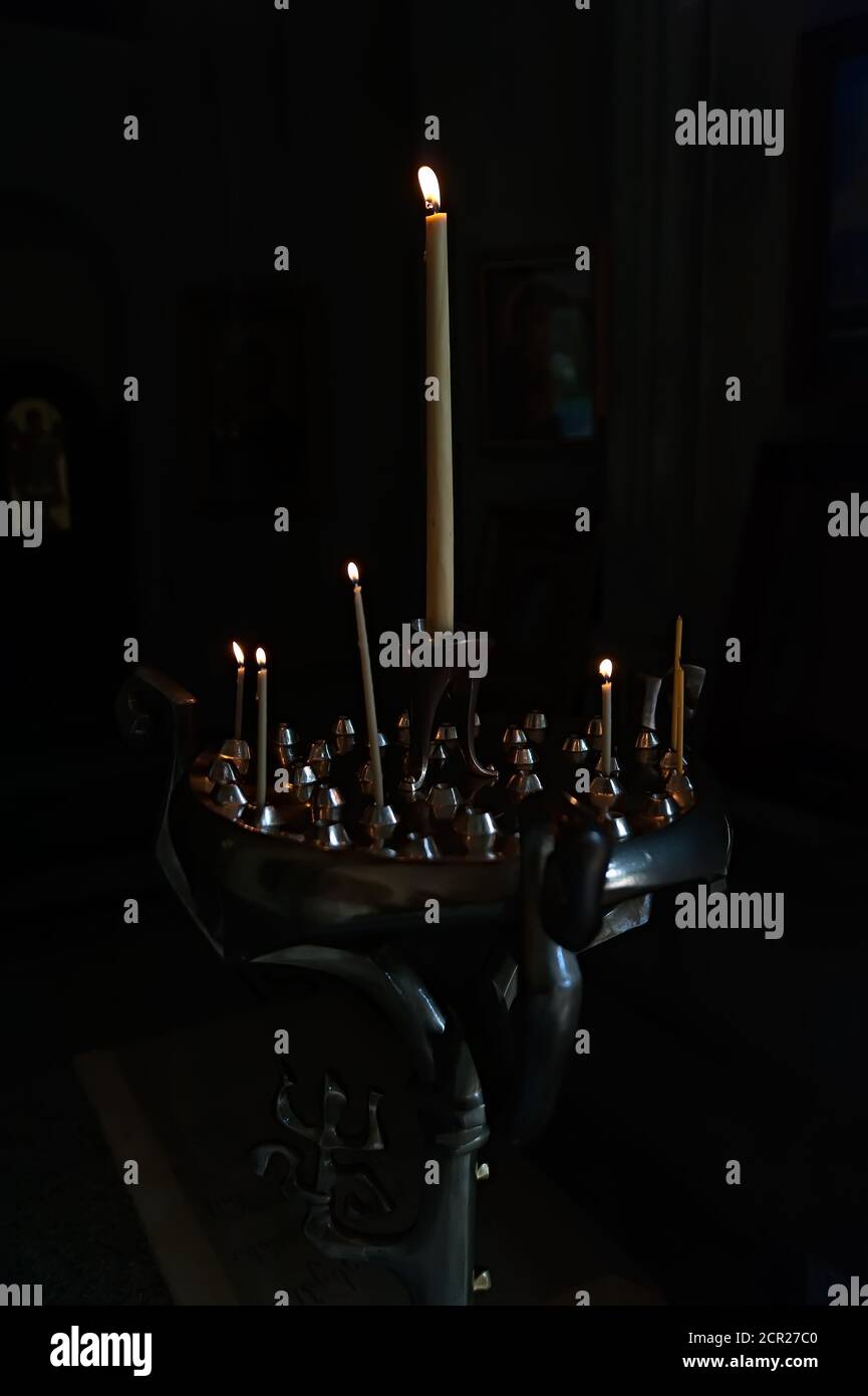 Candela bastone con alcune candele che bruciano nella stanza vuota scura Foto Stock