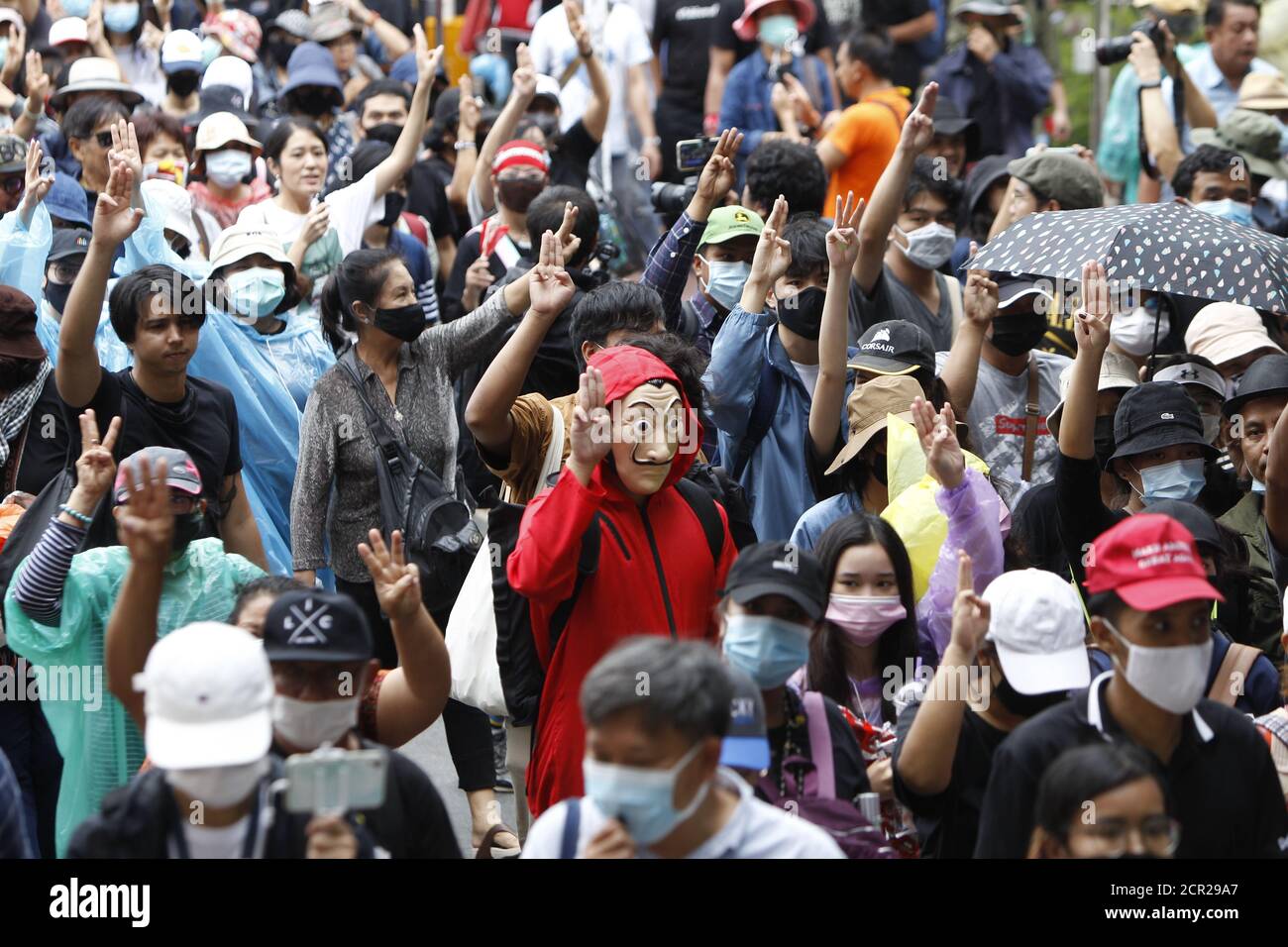 I manifestanti anti anti anti-governativi fanno un saluto a tre dita durante le loro passeggiate dall'Università di Thammasat a Sanam Luang. I manifestanti pro-democrazia si sono conversi oggi nello storico cuore reale di Bangkok per chiedere le dimissioni del governo sostenuto dai militari e le riforme della monarchia, a lungo considerato un argomento tabù in Thailandia. I dimostranti si sono riuniti per la prima volta nel campus universitario di Thammasat su un campo di calcio universitario che è stato teatro di un massacro di studenti di sinistra da parte di paramilitari pro-regime nel 1976. Foto Stock