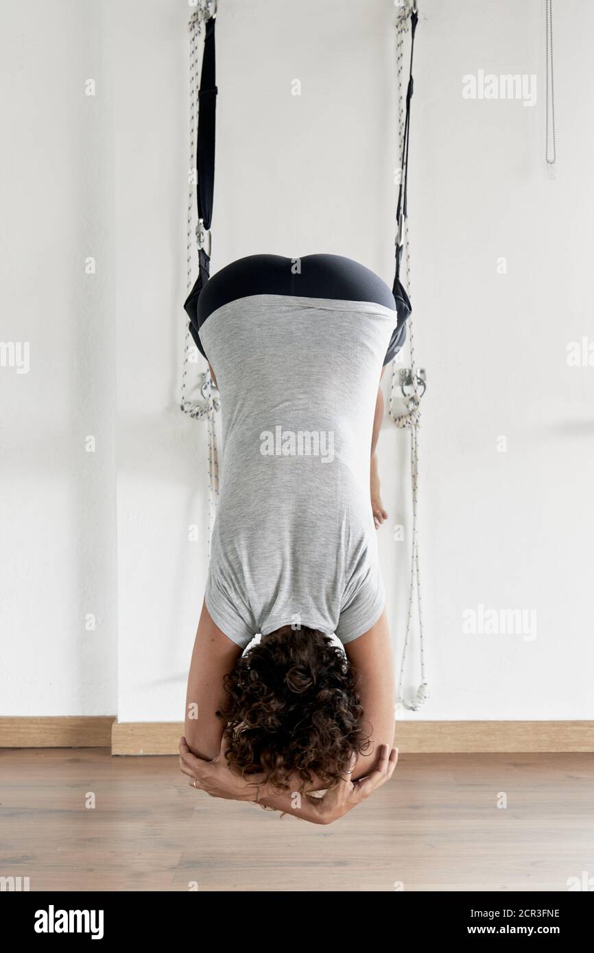 Giovane donna che pratica lo yoga iyengar usando corde da parete in studio, supta padangusthasana Foto Stock