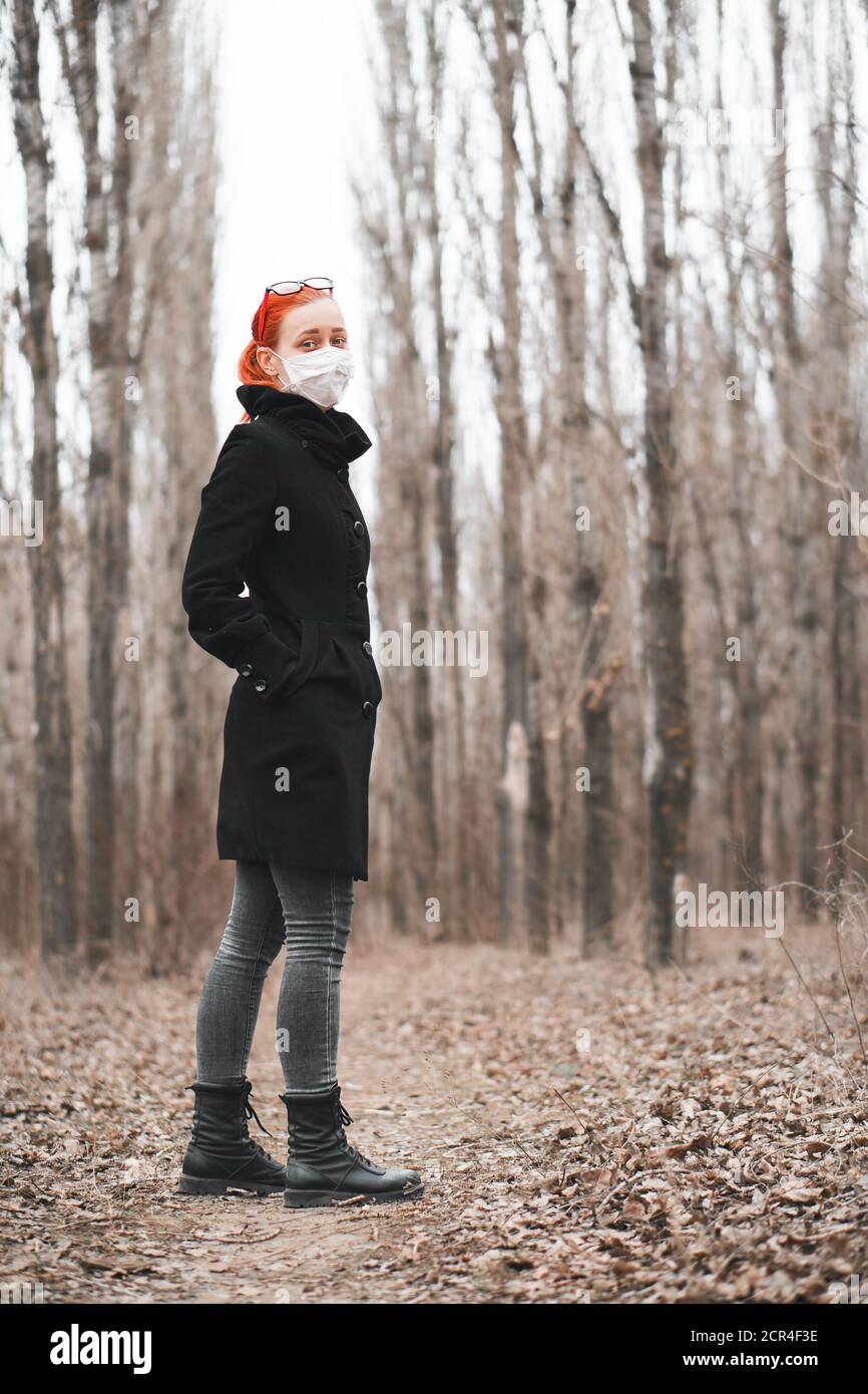 Ragazza in maschera e occhiali passeggiate nel parco. Camminare durante l'epidemia di covid-19. Metodi di protezione antivirus. Foto Stock