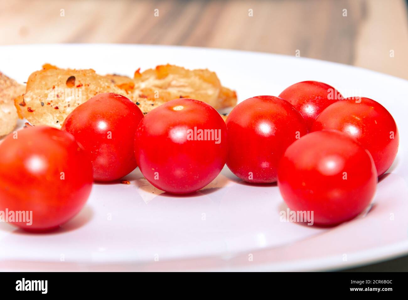 Primo piano di pomodori ciliegini rotondi su un bianco piastra Foto Stock