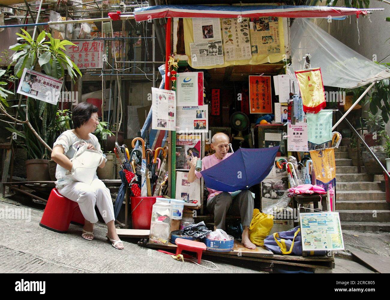 Ombrello mender ho Hung-hee (R) parla con un cliente mentre lavora nel suo  negozio di Hong Kong realizzato localmente il 5 settembre 2002. Ho, 77  anni, ha stabilito un Guinness World Record