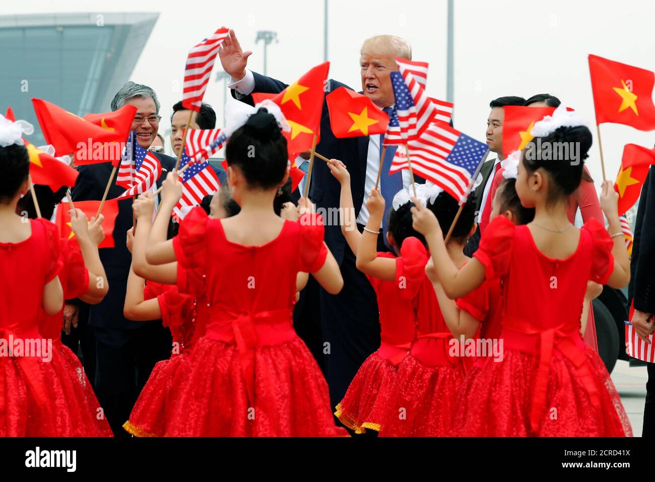 I bambini con bandiere salutano e il presidente degli Stati Uniti Donald Trump salirà a bordo dell'Air Force 1 per partire per le Filippine dall'aeroporto internazionale noi Bai di Hanoi, Vietnam, 12 novembre 2017. REUTERS/Jonathan Ernst Foto Stock