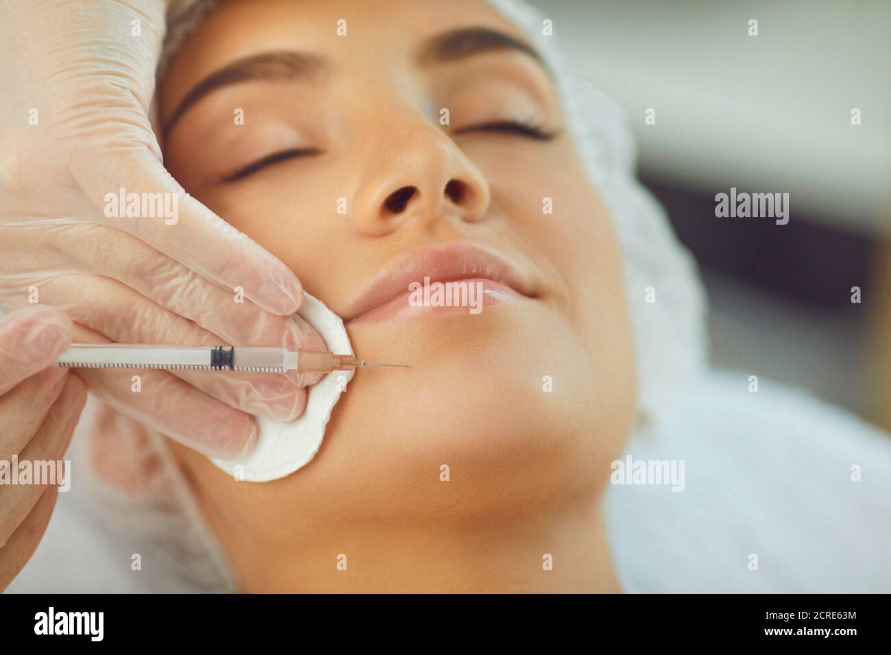 Donna che riceve la bellezza facciale iniezione botox al mento da professionista cosmetologo Foto Stock