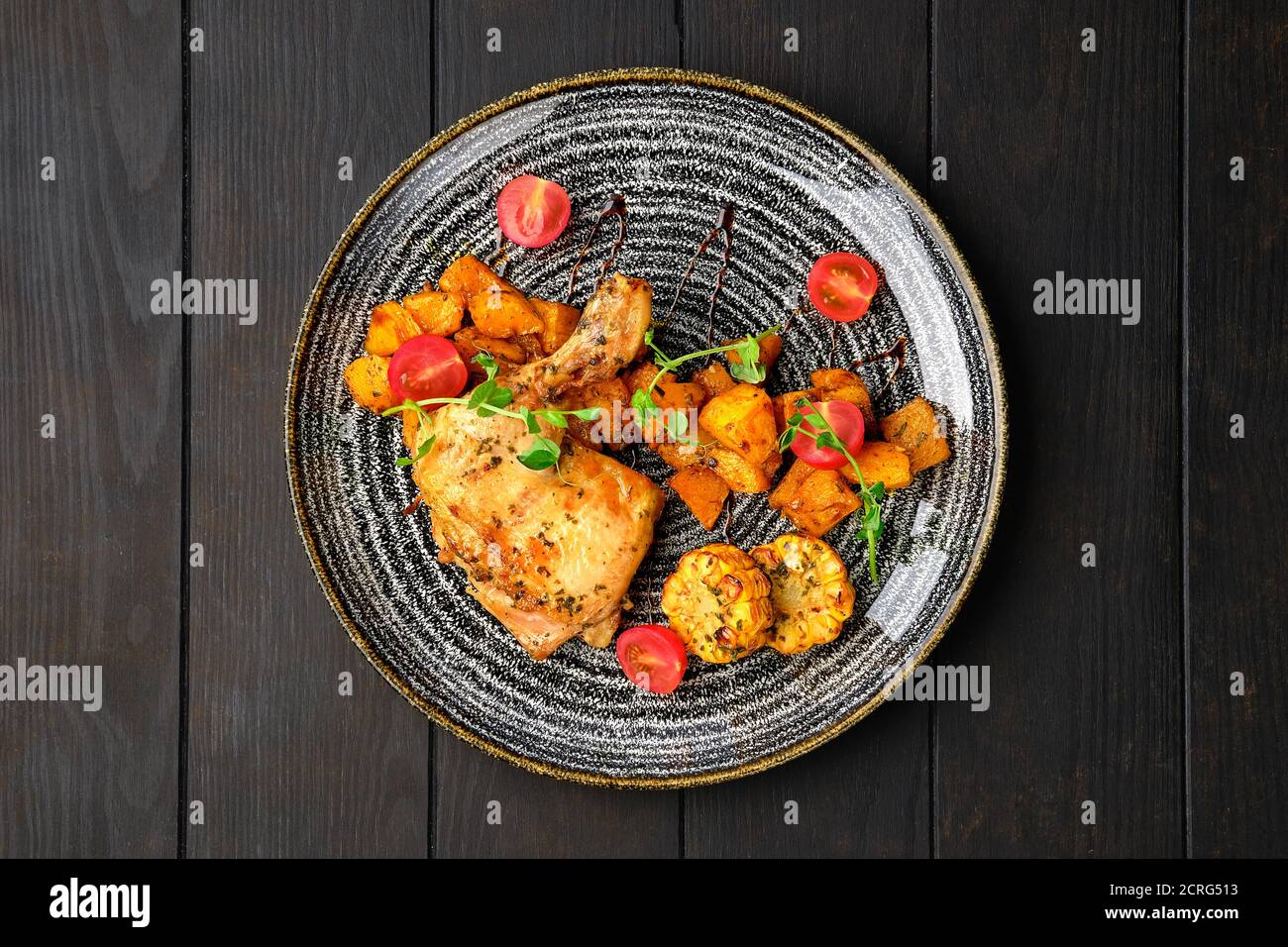 Vista dall'alto della coscia di pollo arrosto con zucca fritta, mais alla griglia sulla pannocchia e ciliegia di pomodoro Foto Stock