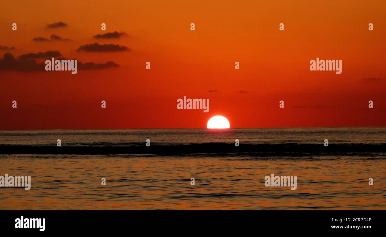 Romantico cielo rosso tramonto sulle calme acque dell'oceano Indiano e un impressionante tramonto vicino all'isola di Mauritius. Foto Stock