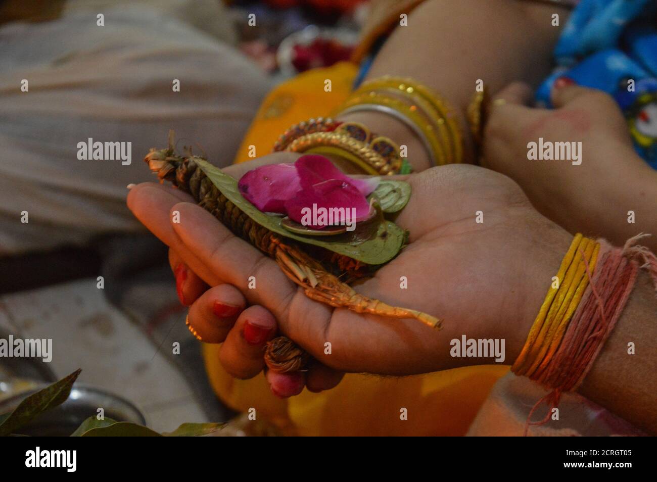 Una coppia indiana che si tiene la mano l'un l'altro e che porta foglia di pianta di betel e rosa per il culto di dio indiano. Foto Stock
