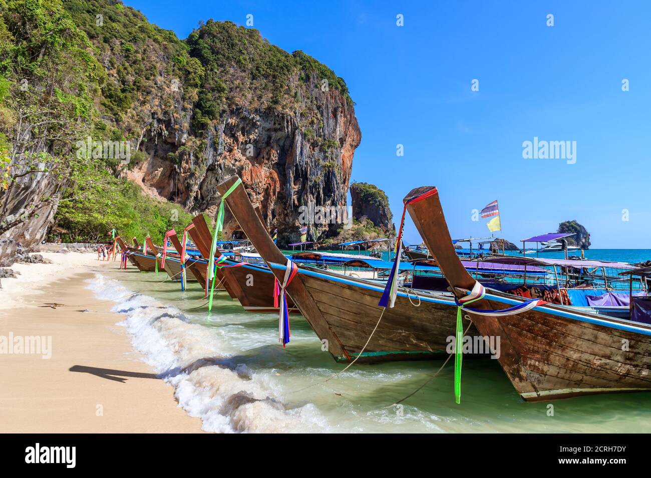 Barca a coda lunga e acque cristalline turchesi con scogliera calcarea e montagna a Phra Nang Beach, Krabi, Thailandia Foto Stock