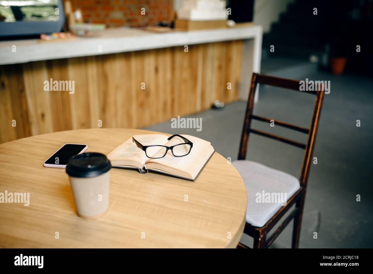 Libro, caffè e bicchieri sul tavolo nel cafe per studenti Foto Stock
