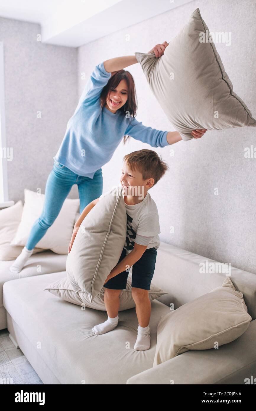 Madre e figlio piccolo che hanno lotta cuscino sul divano a. casa Foto Stock