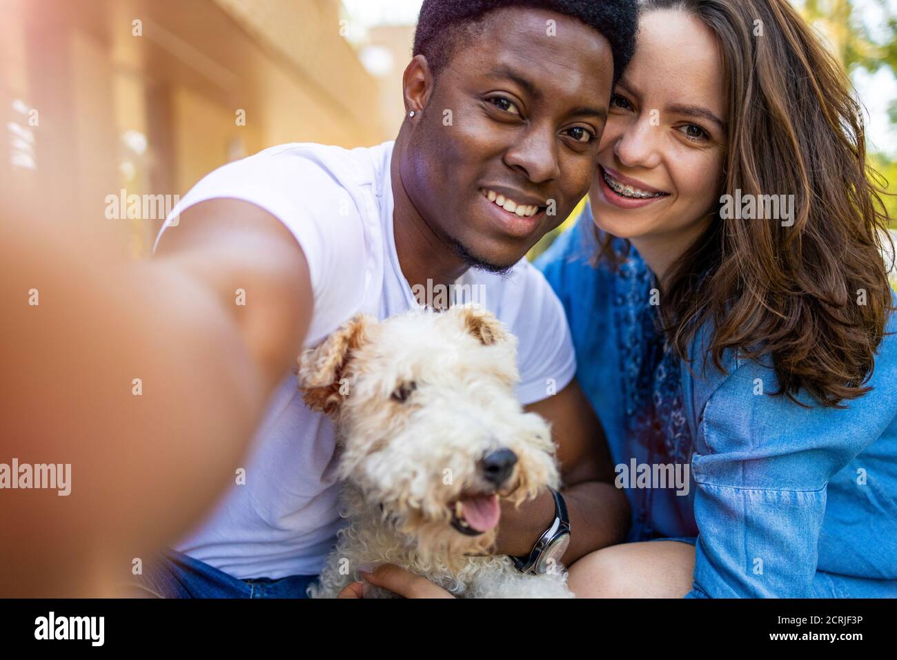 Felice giovane coppia con il loro cane animale domestico all'aperto Foto Stock