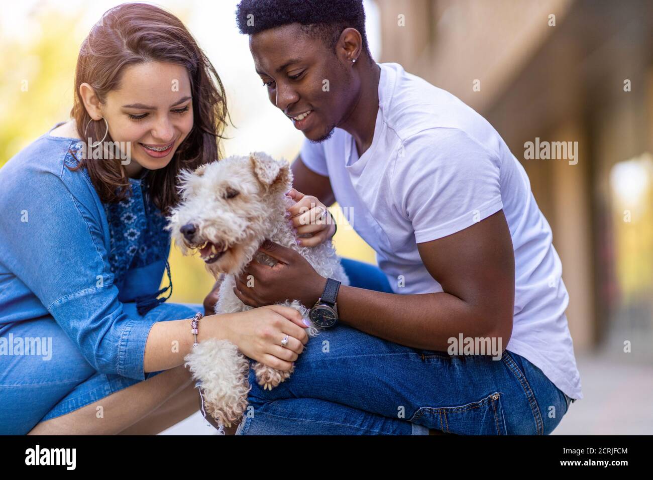 Felice giovane coppia con il loro cane animale domestico all'aperto Foto Stock