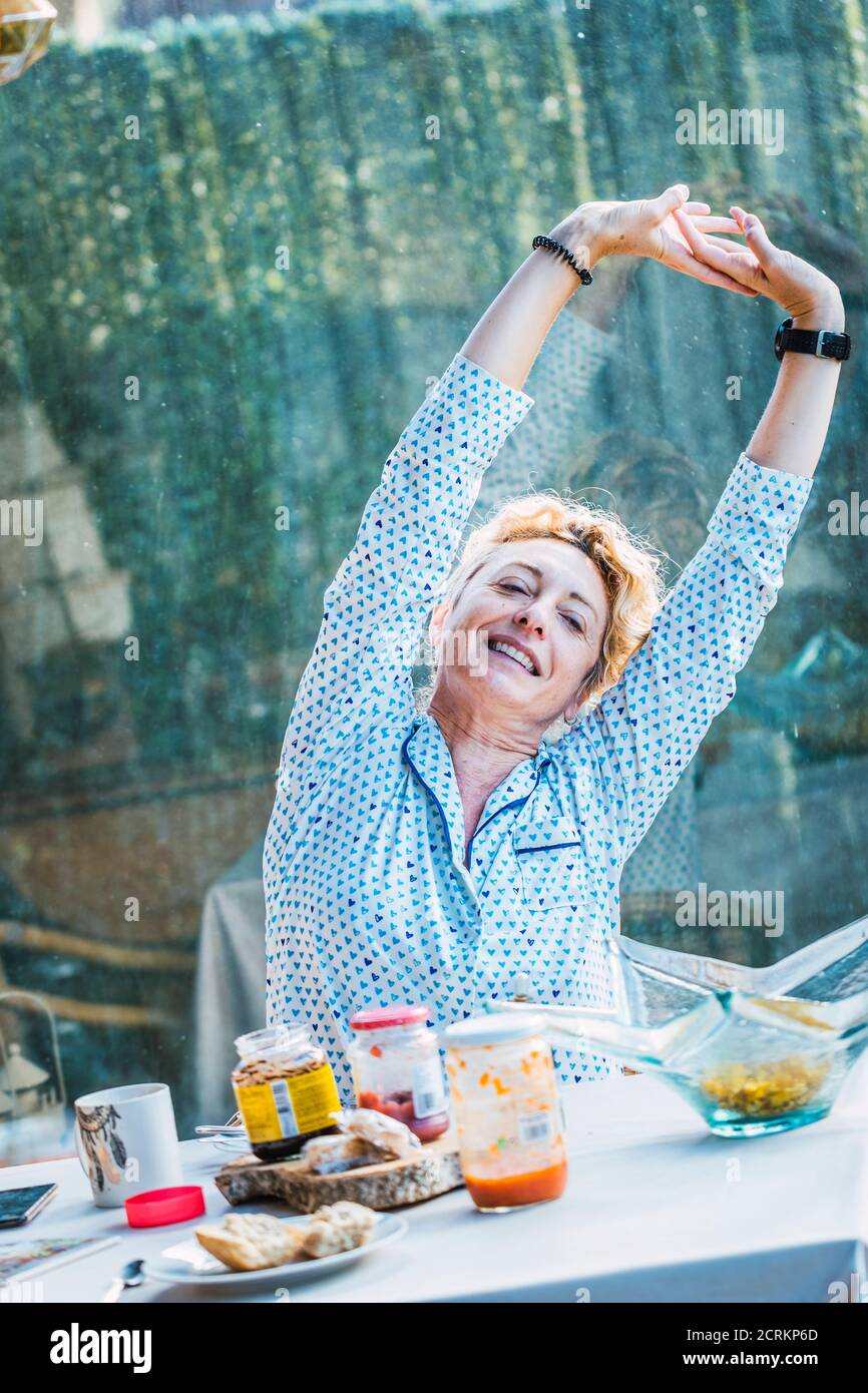 Bionda giovane donna matura in pigiama a casa a colazione tempo in un Foto Stock