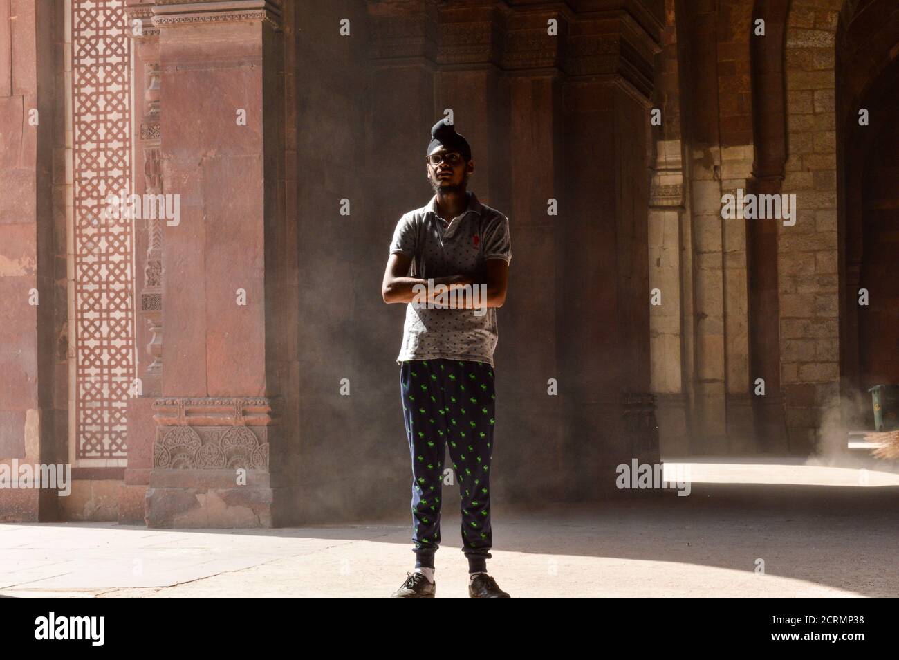 Un ragazzo indiano che dà la posa per sparare di moda all'interno del vecchio forte e l'impiegato di ASI che pulisce la zona. Foto Stock