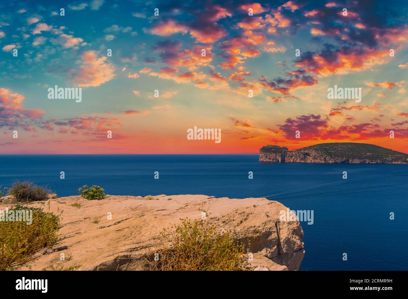 Paesaggio della costa di Capo Caccia, in Sardegna, al suggestivo tramonto con nuvole rosse Foto Stock