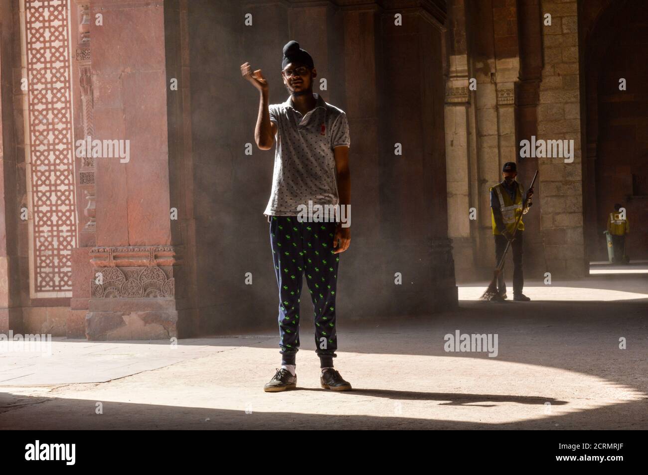 Un ragazzo indiano che dà la posa per sparare di moda all'interno del vecchio forte e l'impiegato di ASI che pulisce la zona. Foto Stock