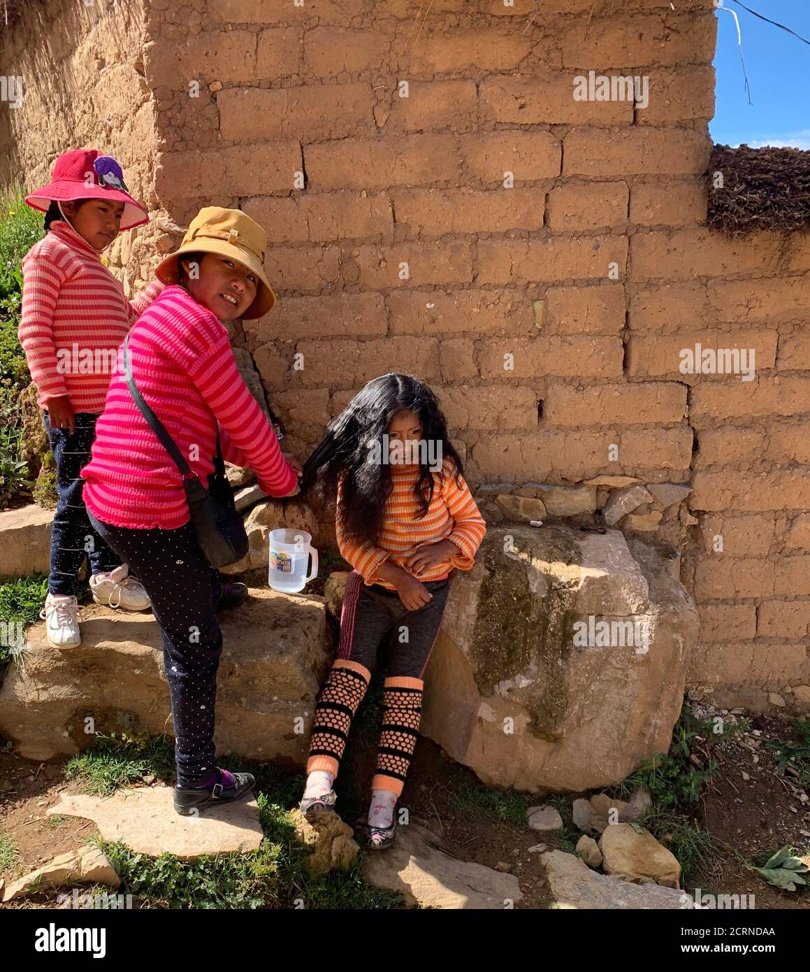Le ragazze carine boliviane si fanno a vicenda acconciature con trecce. Divertenti adorabili bambini Aymara provenienti da Isla del Sol, Boliiva, Sud America. Amico di infanzia Foto Stock