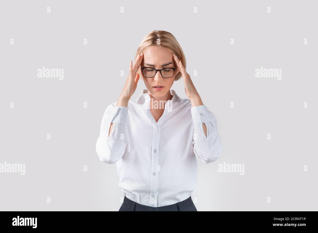 Stanco dipendente di ufficio che soffre di mal di testa su sfondo studio chiaro Foto Stock