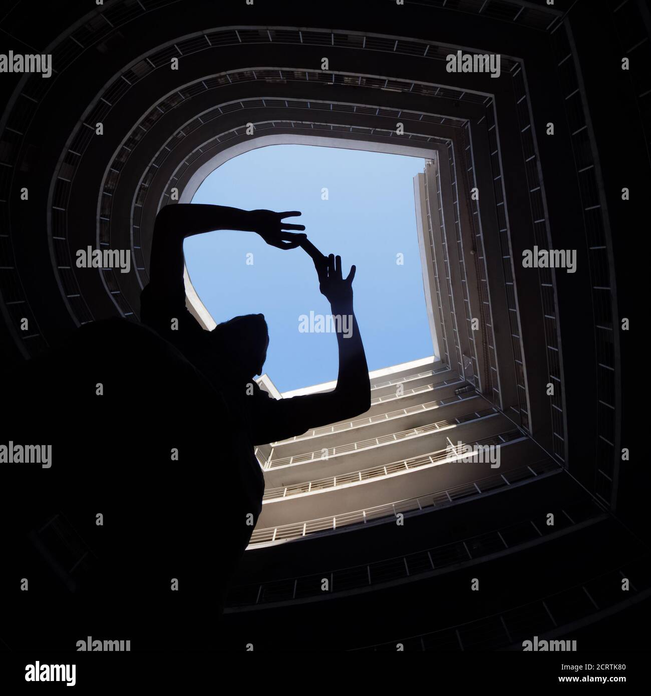 Fotografo in grande città. Uomo che fa una foto sul cellulare in città. Moderno edificio rotondo con cielo blu sulla sommita'. Silhouette di un uomo che prende il Foto Stock
